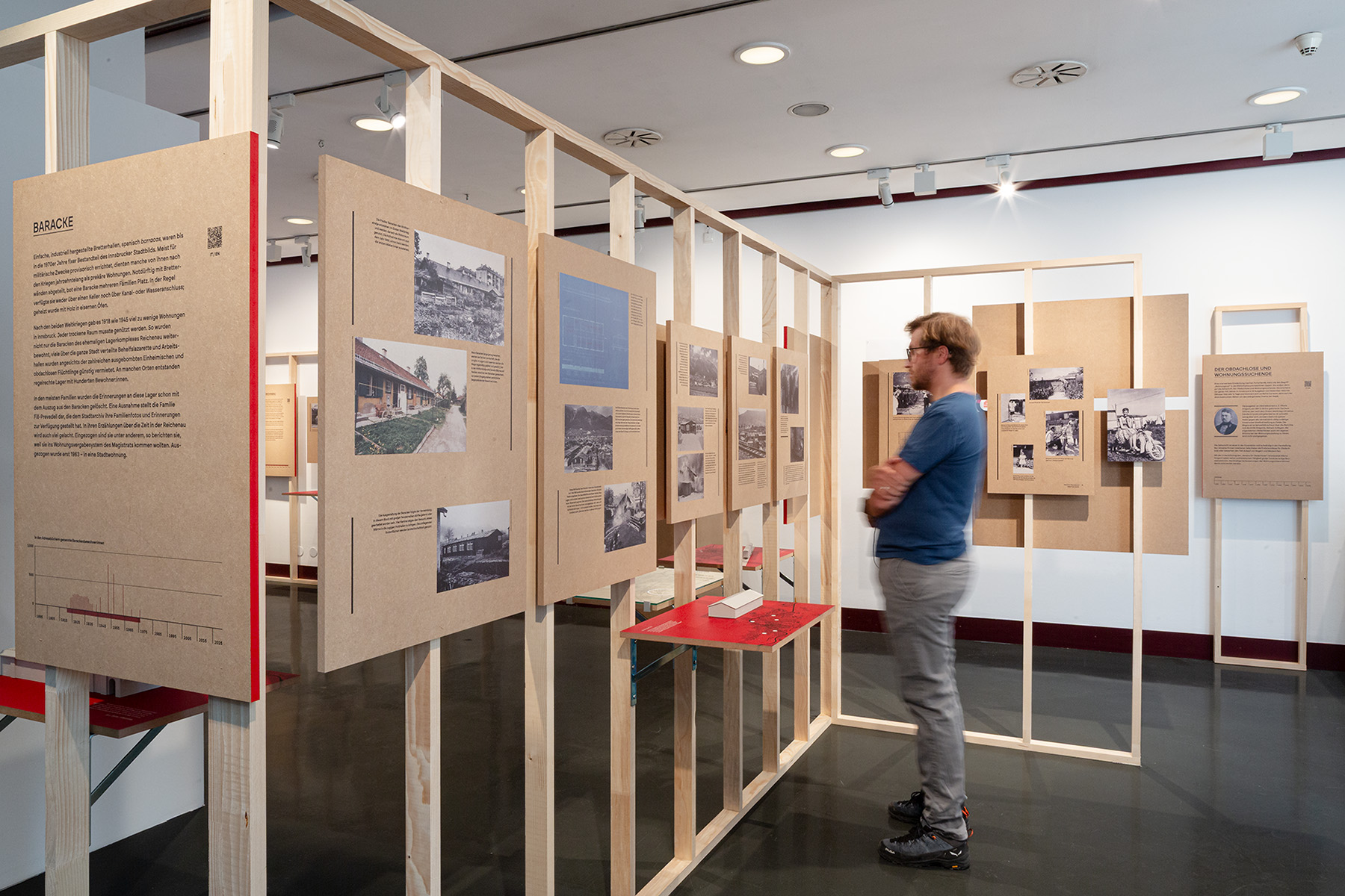 Mann steht vor Ausstellungswand aus Holzgerüst